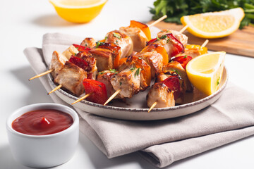 Delicious grilled chicken skewers with capsicum, lemon, salad and ketchup on a plate over the table. Chicken kebab. Healthy food concept.
