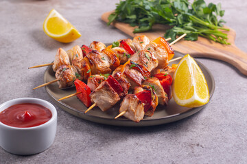 Delicious grilled chicken skewers with capsicum, lemon, salad and ketchup on a plate over the table. Chicken kebab. Healthy food concept.