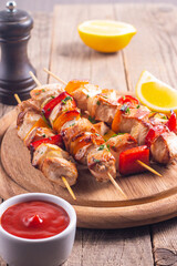 Delicious grilled chicken skewers with capsicum, lemon, salad and ketchup on a plate over the table. Chicken kebab. Healthy food concept.