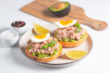 Two delicious tuna open sandwiches with avocado and boiled eggs. Tuna toast.