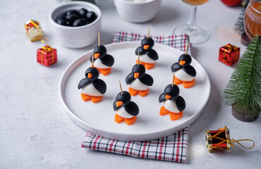Mozzarella, carrots and black olives appetizer in the form of penguin in a plate for Christmas holidays