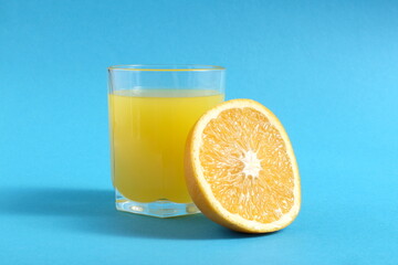  On a blue background there is a glass of freshly squeezed orange juice.