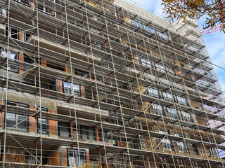 Scaffolding pattern on the facade of an urban construction site. Engineering precision, geometry and transformation in architectural development.