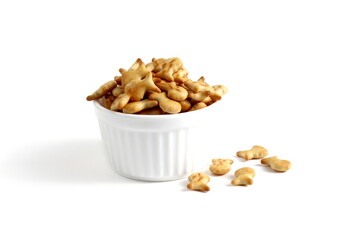 There is a ceramic bowl with fish cookies on a white background.	