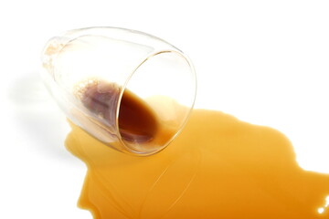 An overturned glass cup of coffee lies on a white background.	
