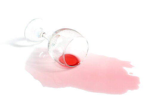 An overturned glass of red wine lies on a white background.	