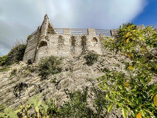 archaic limestone fortification atop rugged cliffs with vibrant greenery and cloudscape backdrop © Наталья Северова