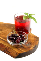 On a white background there is a transparent glass with cherry compote on a wooden board.	