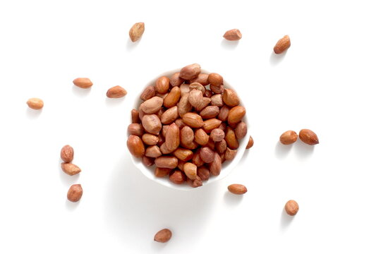 There is a white bowl with peanuts on a white background. - Powered by Adobe