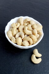There is a bowl of cashew nuts on a black background.
