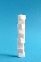 Sugar cubes stacked in a tower on a blue background.