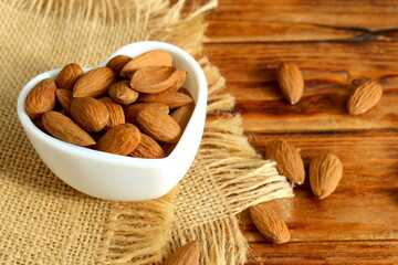 There is a bowl of almonds on the wooden table.