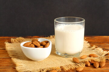 There is almond milk with almonds on the wooden table.