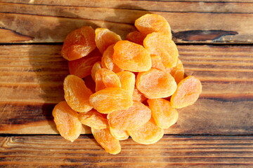 There are dried apricots on the wooden table.