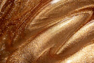 Glowing golden shimmering cosmetic texture of gel or body spray. Background texture for backdrops or mapping.