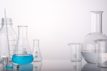 Glass flasks and cylinder beakers in medical science lab on white background. Space for products presentation.
