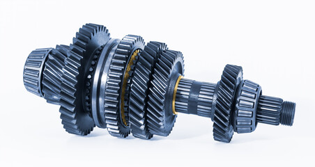 Internal gear mechanism in manual transmission part on a white background. Closeup of car metallic blue gearbox shaft with various steel cogwheels or golden synchronizer rings. Mechanical engineering.