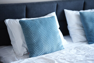 On the bed there is a decorative blue pillow in a velvet cover with a geometric herringbone or...