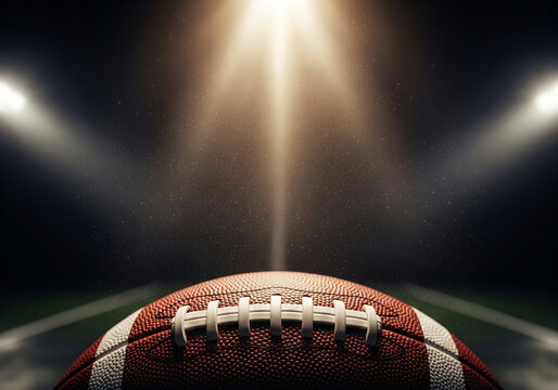 Close up of an american football on a dark field under bright stadium lights with dramatic spotlights illuminating the ball