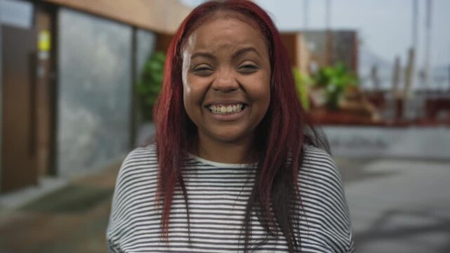 African american woman clenching fists outside a building entrance with intense expression; determination.
