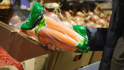 hand selecting fresh vegetables from a grocery display filled with colorful produce
