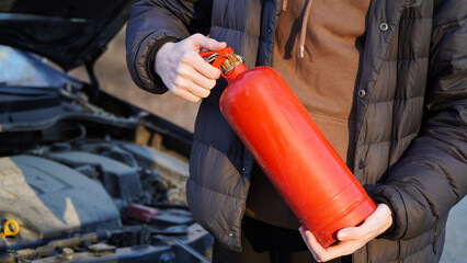 Man with a fire extinguisher helping a person with a car in the flame