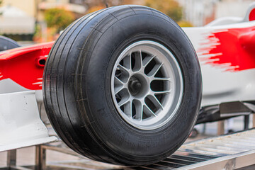 Obraz premium Formula 1 car with front right wheel missing, showing wheel hub and suspension components Red vehicle with white accents and UPS sponsorship branding Setting suggests a maintenance area or pit stop