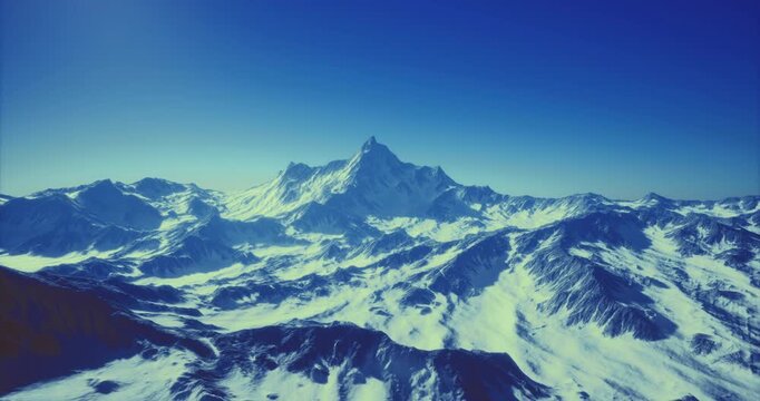 Majestic peaks rise sharply from the snowy landscape, illuminated by the first light of day. A serene blue sky frames this breathtaking view of winters beauty.