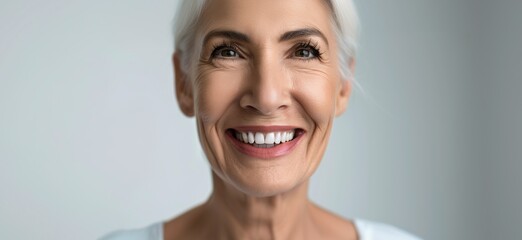Close-up of a cheerful senior woman with natural gray hair and radiant white smile, representing positivity, wellness, and graceful aging.