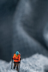 A miniature mountain climber figurine on a fuzzy fleece lining resembling a snow-covered surface,...