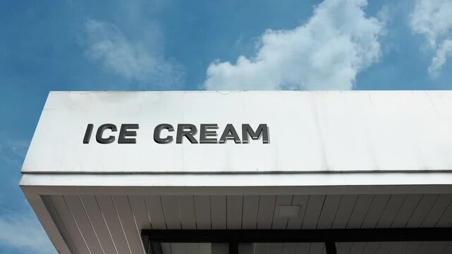 Ice Cream word sign clearly displayed on the commercial retail building facade beneath a clear blue sky, signifying a shop or facility selling frozen desserts and sweet consumables.