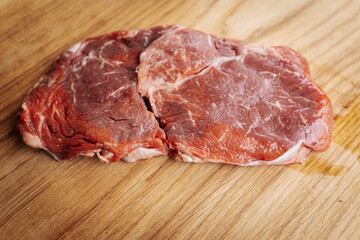 Close-up of raw, marbled meat cuts, freshly sliced and ready for cooking or grilling, showcasing texture and quality in a culinary preparation setting.