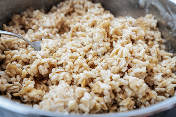 Close-up of cooked whole grain barley or oats in a bowl with a spoon, showcasing a fluffy, hearty texture perfect for a nutritious meal or side dish.