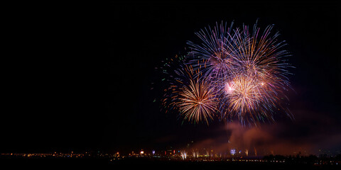New Year's Eve night sky with fireworks exploding over the city. Bright colors and a festive atmosphere. Cityscape view.