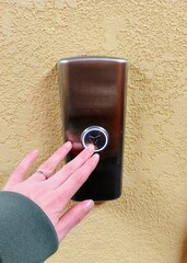 Woman's hand presses the button on the door. Close-up.