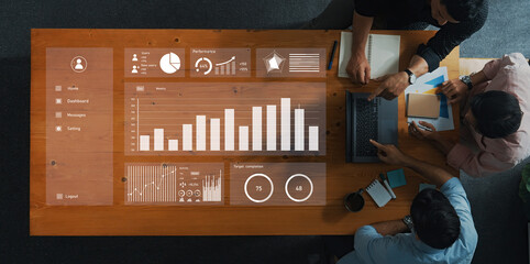 A team collaborates over a table featuring a digital dashboard displaying performance metrics, charts, and graphs. The modern office environment promotes teamwork and productivity. Axiom