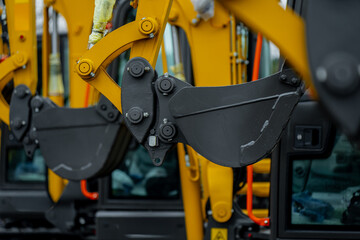 Excavator arm assemblies featuring reinforced steel buckets, hydraulic pivot joints and mechanical connection points arranged in industrial equipment lineup