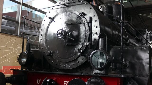 A black train engine sits inside a building