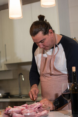 Man preparing raw pork ribs for cooking in kitchen