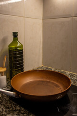 Frying pan on stove close-up, salt, oil in bottle on table.