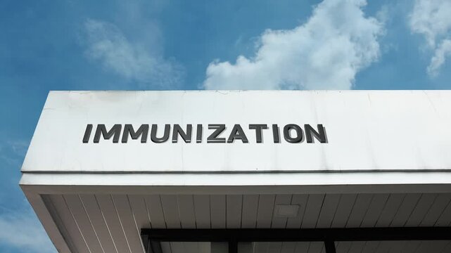 Immunization word sign clearly displayed on the public health or medical building facade beneath a clear blue sky, signifying a facility dedicated to providing vaccinations and preventative health