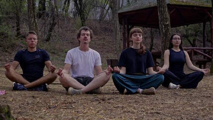 A diverse group of friends practices meditation and yoga outdoors in a serene forest, promoting wellness, inner peace, and a healthy lifestyle.