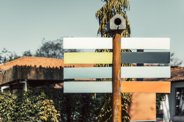 Colorful blank directional sign mockup with empty panels on a wooden pole under bright daylight, perfect template for travel, tourism or navigation design in outdoor environment