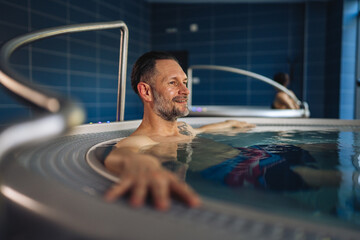 Happy man relaxing in hot tub spa center