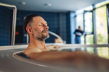 Happy man relaxing in hot tub spa center