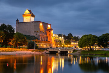 Obraz premium Narva Castle illuminated at night by the river, Estonia.