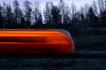 Bullet train in high speed at twilight through the forest, an abstract stylized motion blur photo. © Naya Na