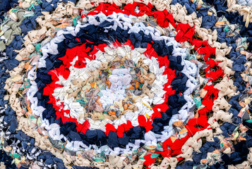 Vintage homespun doormat made from strips of cloth as background. Texture of a homemade rug from different fabrics. Round knit mat