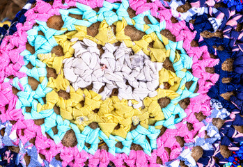 Vintage homespun doormat made from strips of cloth as background. Texture of a homemade rug from different fabrics. Round knit mat