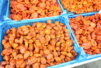 Organic dried apricots in plastic crates at a farmers market. Large pile of dried apricots, dried fruits, healthy dessert, vegetarian food